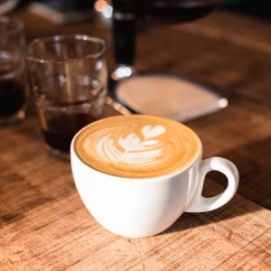 A closeup shot of a cup of hot cappuccino with hearts from foamed milk on it