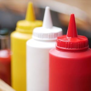 Condiments in various colors are arranged neatly for serving food.